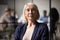 Headshot portrait of middle-aged businesswoman posing in office