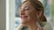 Headshot portrait of smiling gorgeous rich middle aged woman smelling fragrance and applying perfume on ears and neck