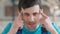 Headshot portrait of young Caucasian service man suffering severe headache indoors. Close-up face of sad stressed