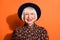 Headshot of positive laughing stylish granny wearing printed blouse hat smiling with red lipstick isolated on bright