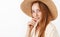 Headshot of stylish charming and flirty redhead girlfriend with freckles in straw hat and trendy yellow blouse biting