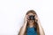 Headshot of young adorable playful blonde woman with cute smile in cobalt color blouse taking photos with black dslr camera on whi