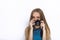 Headshot of young adorable playful blonde woman with cute smile in cobalt color blouse taking photos with black dslr camera on whi