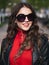Headshot of young happy fashionable elegant brown-haired woman in sunglasses with long curly hair enjoying spring warm weather at