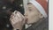 Headshot of young sad man sitting behind glass on windowsill in New Year hat drinking tea or coffee from cup. Close-up