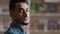 Headshot young serious pensive handsome bearded arab guy indian model standing indoors looking away thinking dreaming