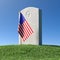 Headstone and small American flag on green grass under blue sky