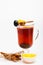 Healing drink concept. Glass with mulled wine or hot tea with grape, cinnamon and honey on white background, close up