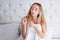 Health And Beauty. Portrait Of Beautiful Sad Young Woman With Long Hair In Hand In Bedroom. Closeup Of Unhappy Female Model