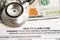 Health claim form with stethoscope and US dollar banknotes, insurance accident medical concept