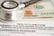 Health claim form with stethoscope and US dollar banknotes, insurance accident medical concept