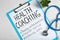 Health coaching written on sheet of paper with stethoscope on white textured background