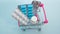 Health concept, pills in a trolley from a supermarket on a blue background, top view, complex treatment of medicines