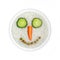 Health food -  rice with vegetable smiling face - eyes cucumber, carrot nose, mouth green peas in circle
