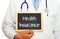 Health Insurance - Doctor holding chalkboard with text