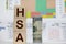 Health Savings Account HSA concept with white piggy bank, stethoscope wood block letters and green background