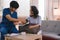 A health visitor is measuring blood pressure a sick elderly woman who is sitting on a sofa at home. This scene