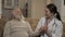 Health visitor talks with senior man at the sofa