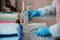 A health worker in blue gloves holds in hands a bottle of saline over the table. Coronavirus concept