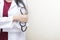 Healthcare background concept. Closeup doctor holding stethoscope standing on white wall with empty space.