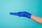 Healthcare concept. Cropped photo of doctor`s hand in a blue glove isolated on teal turquoise background