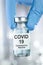 Healthcare cure concept with a hand in blue medical gloves holding Coronavirus, Covid 19 virus, vaccine vial