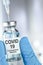 Healthcare cure with a hand in blue medical gloves holding Coronavirus, Covid 19 virus, vaccine vial