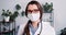 Healthcare expert. Beautiful happy Caucasian female doctor wears lab coat, touches eyeglasses posing at clinic office.