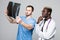 Healthcare, medical and radiology concept - two doctors looking at x-ray on gray background