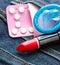 Healthcare medicine, contraception and birth control. oral contraceptive pills, condom and red lipstick in denim pocket.