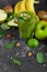 Healthful fruits and a glass of cocktail from kiwi on a dark gray stone background. Juicy ingredients for vegan diets.