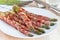 Healthy appetizer, green asparagus wrapped with bacon on white p