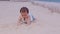 Healthy asian baby toddler crawling on the beach to learn to crawl outdoors. Adorable baby keeping her belly and legs down on sand