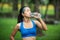 Healthy athletic asian woman is drinking pure water from the bottle refreshing herself after running.