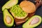 Healthy avocado burger on the wooden board - traditional Mexican dish. Vegetarian avocado sandwich on the black kitchen background