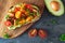 Healthy avocado toast with cherry tomatoes, close up table scene over a dark background