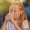 Healthy baby milk - Portrait of a beautiful redhead girl drinking fresh milk outdoors. Summer drink