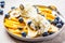 Healthy banana split with mango, chocolate and whipped cream on gray plate