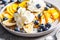 Healthy banana split with mango, chocolate and whipped cream on gray plate