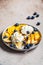 Healthy banana split with mango, chocolate and whipped cream on gray plate