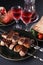 Healthy barbecued lean cubed pork kebabs served with tomato,pita, greens, garnet and two glasses of red drink, close up