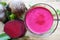 Healthy beet juice and raw beetroot on wooden table