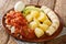 Healthy Bermuda breakfast of salted cod with onion tomato sauce, boiled potatoes, eggs, fresh banana and avocado close-up in a