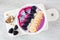 Healthy blackberry smoothie bowl with coconut, bananas, dragon fruit and granola on a marble platter
