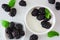 Healthy bowl of yogurt with blackberries, close up top view over white marble