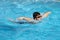 Healthy boy butterfly style swims in swimming pool