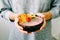 Healthy breackfast in bowl of coconut with nasturtium flowers in hands on white background