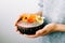 Healthy breackfast in bowl of coconut with nasturtium flowers in hands on white background