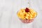 Healthy breakfast in bowl with golden corn flakes, ripe slice cherry on white wood board. Decorative border with copy space.