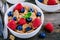 A healthy breakfast bowl. Whole grain cereal with fresh blueberries and raspberries on wooden background.